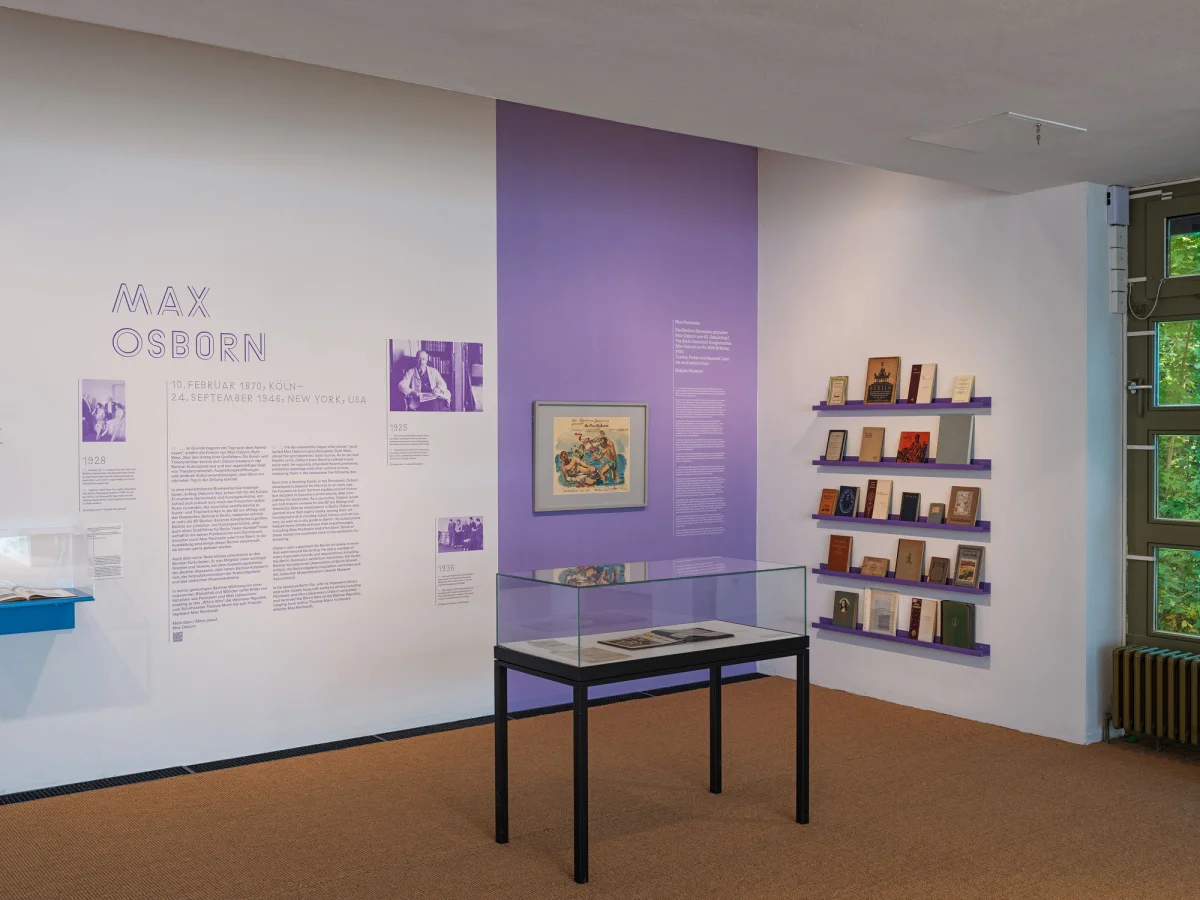 Exhibition section about Max Osborn, with wall texts, a painting, a glass case and shelves of books.