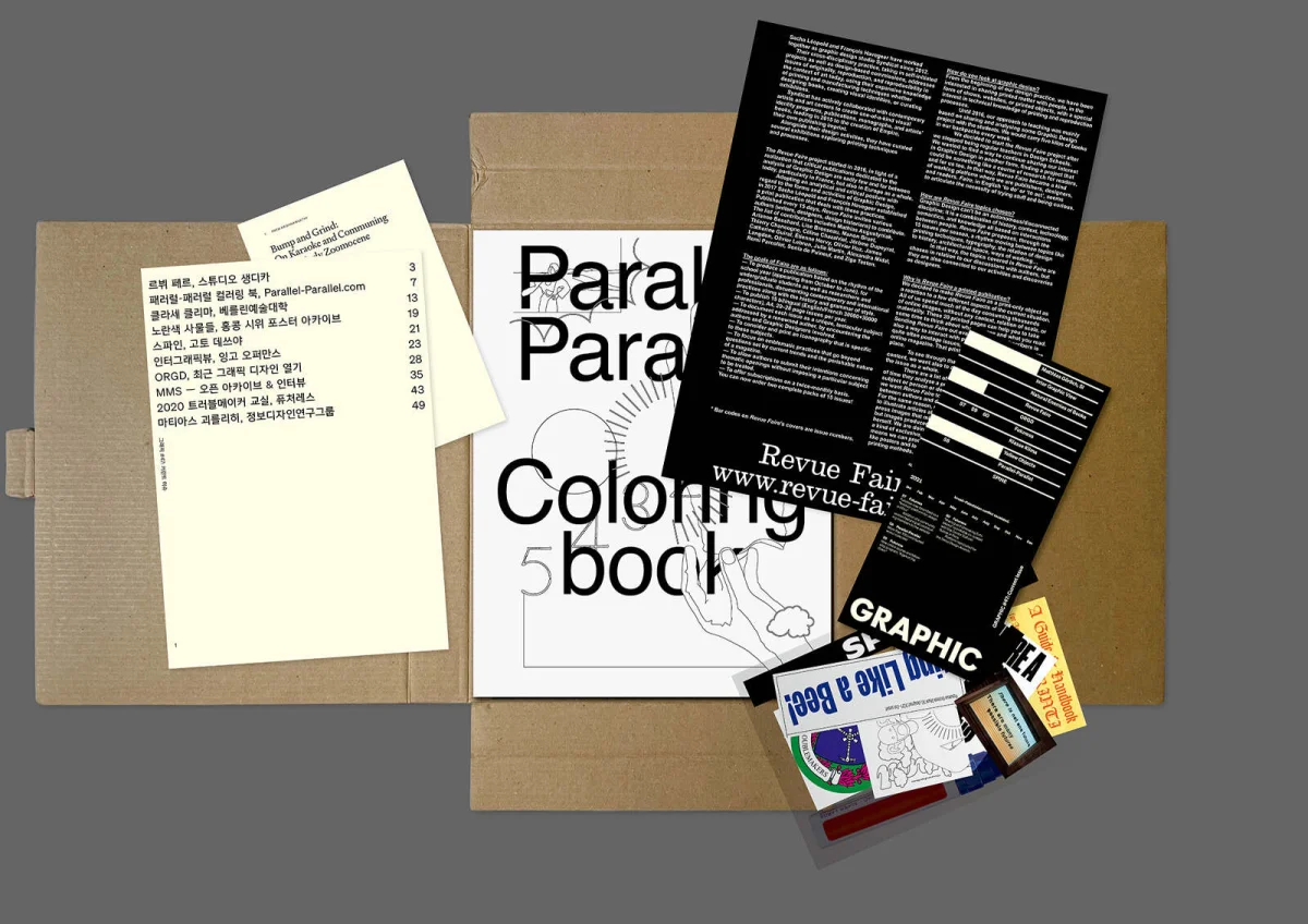 GRAPHIC box with publications laid out, including a black-and-white colouring book and a black Revue Faire issue.