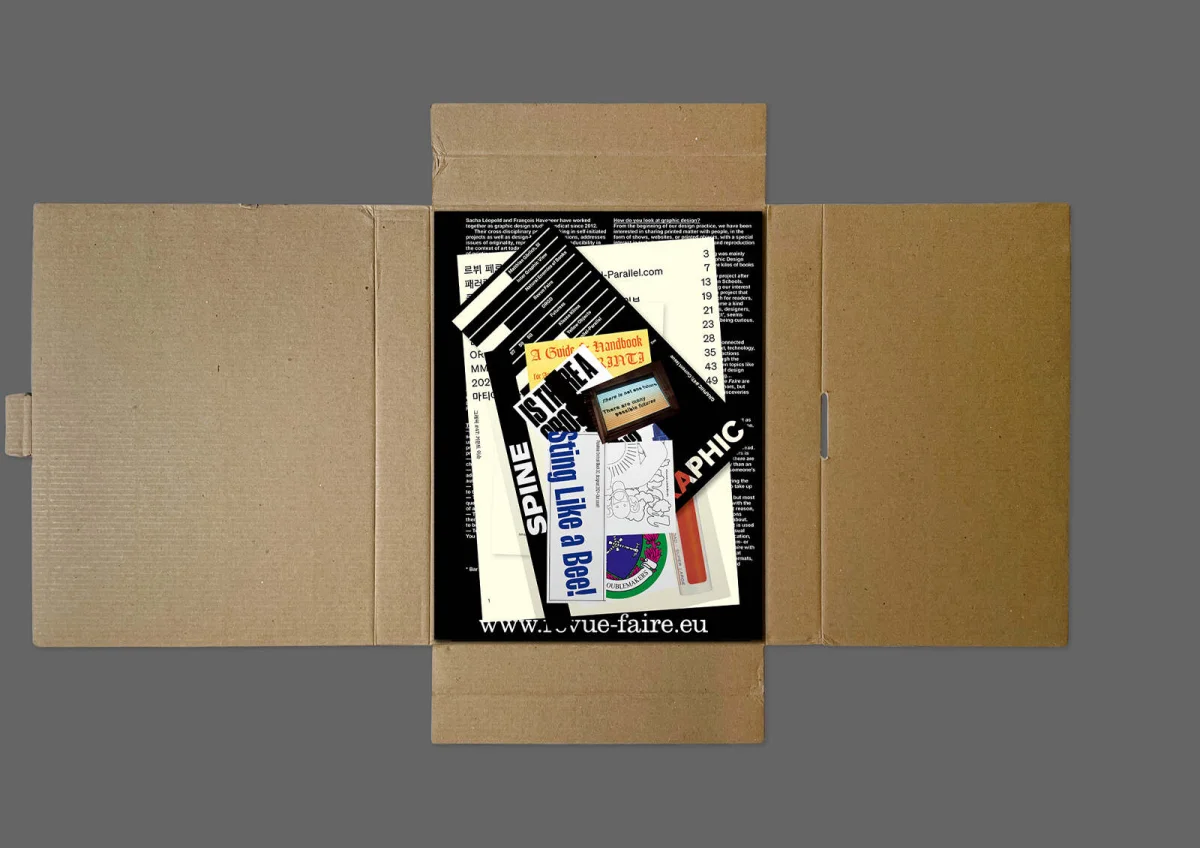 Open brown GRAPHIC box containing a stack of differently designed publications and stickers.