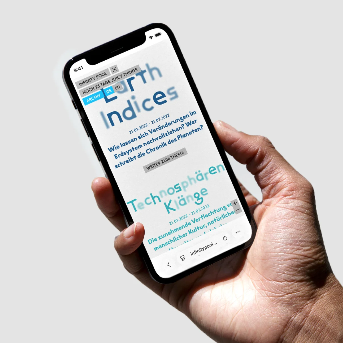 Hand holding a smartphone displaying the Infinity Pool website and the themes “Earth Indices” and “Technosphärenklänge”.