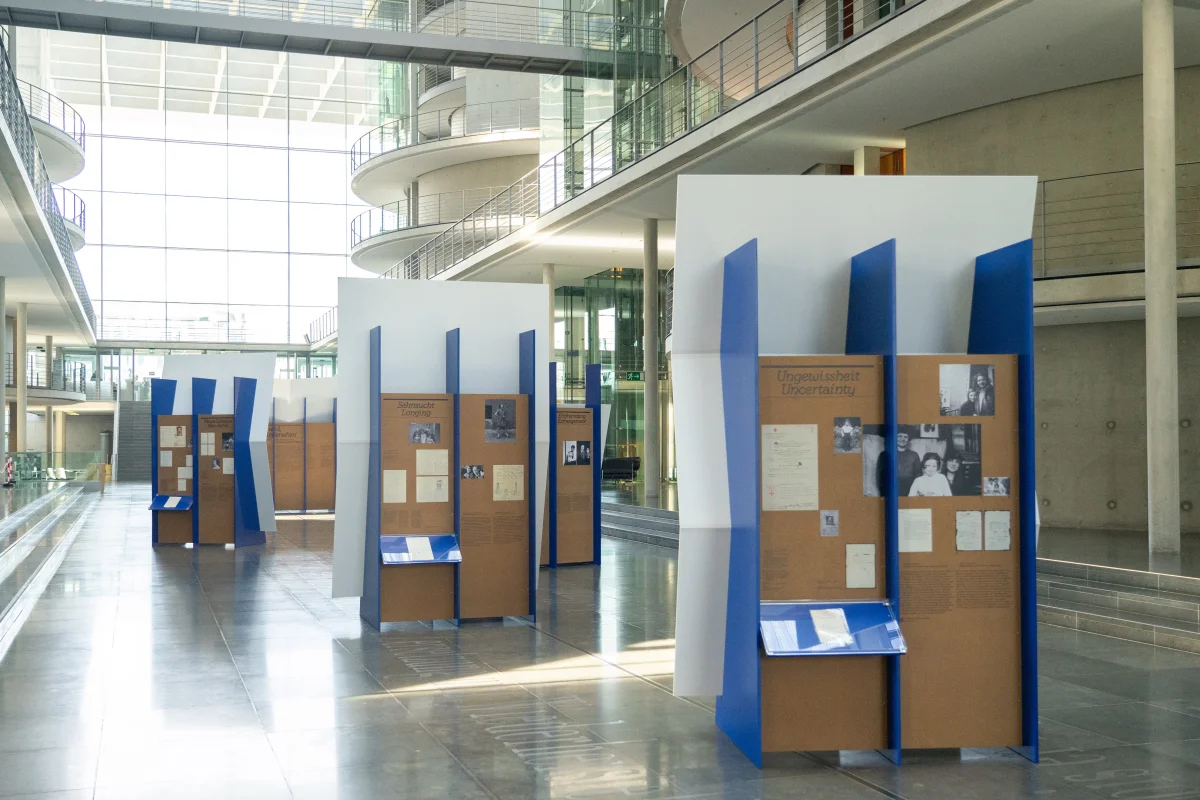 Blue exhibition modules in an atrium, with brown reverse panels presenting Kindertransport letters, photographs and information.