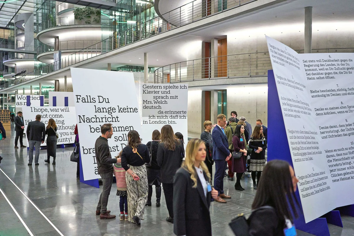 Visitors among tall white text panels at the Kindertransport exhibition in an atrium.