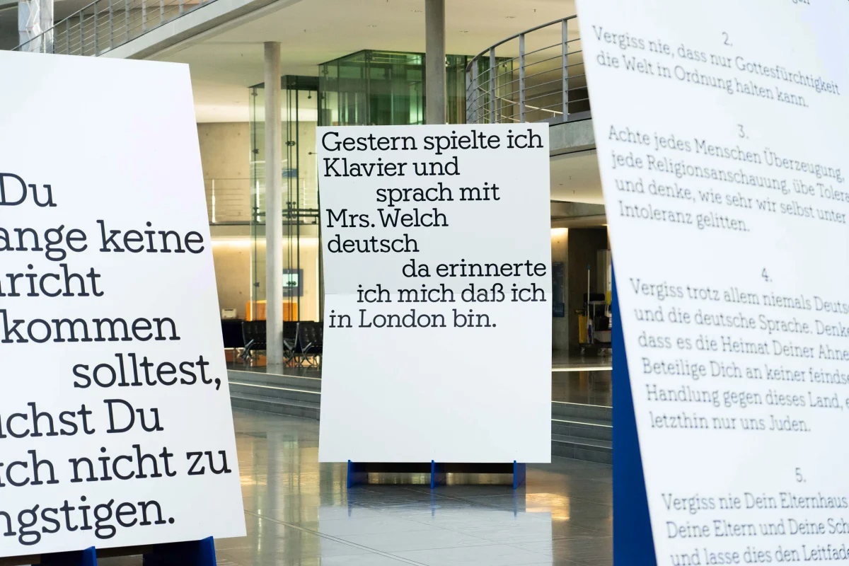 White exhibition panels with large letter quotations, including a German passage about playing piano and speaking German with Mrs. Welch.