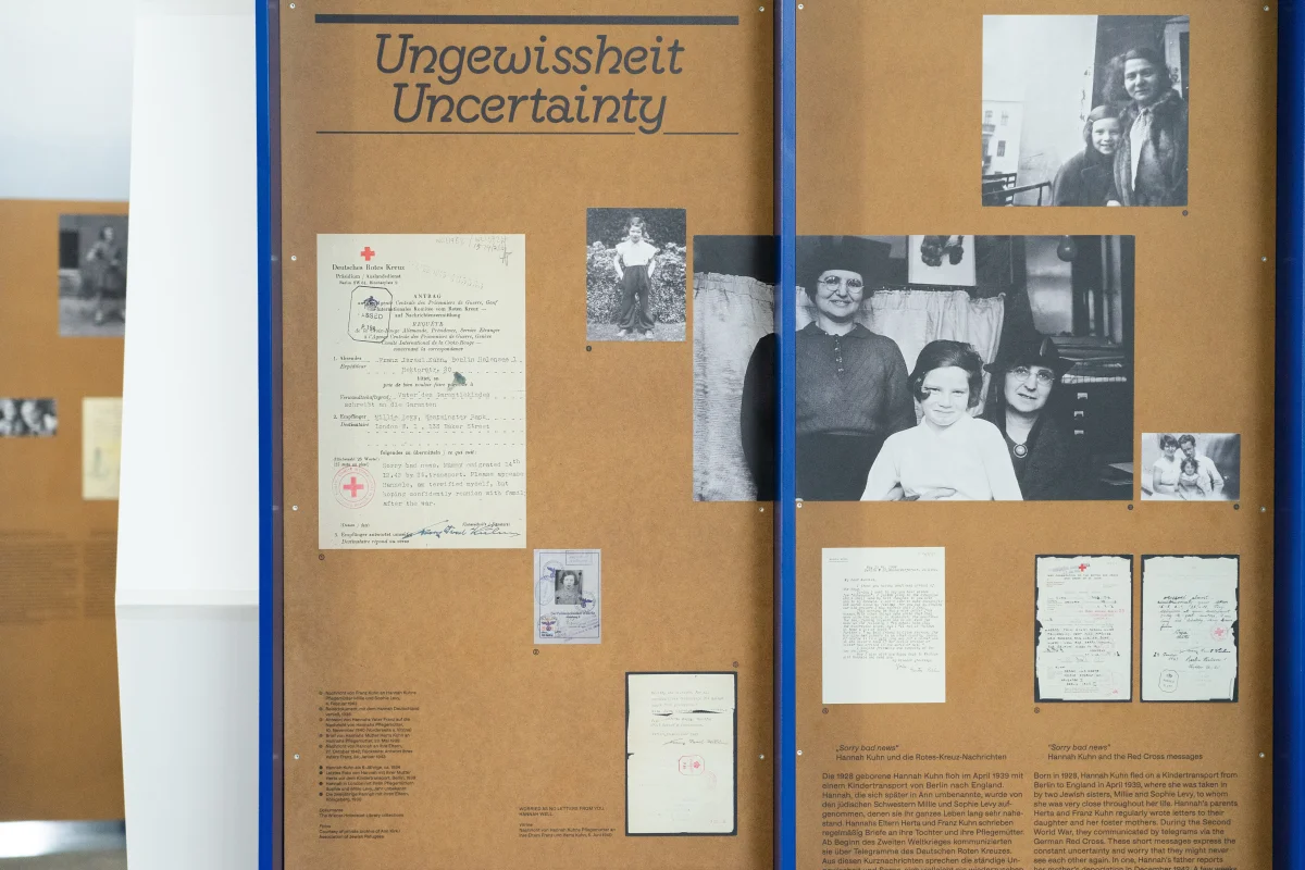 Brown exhibition panel headed “Ungewissheit / Uncertainty”, with letters, forms and historical family photographs.
