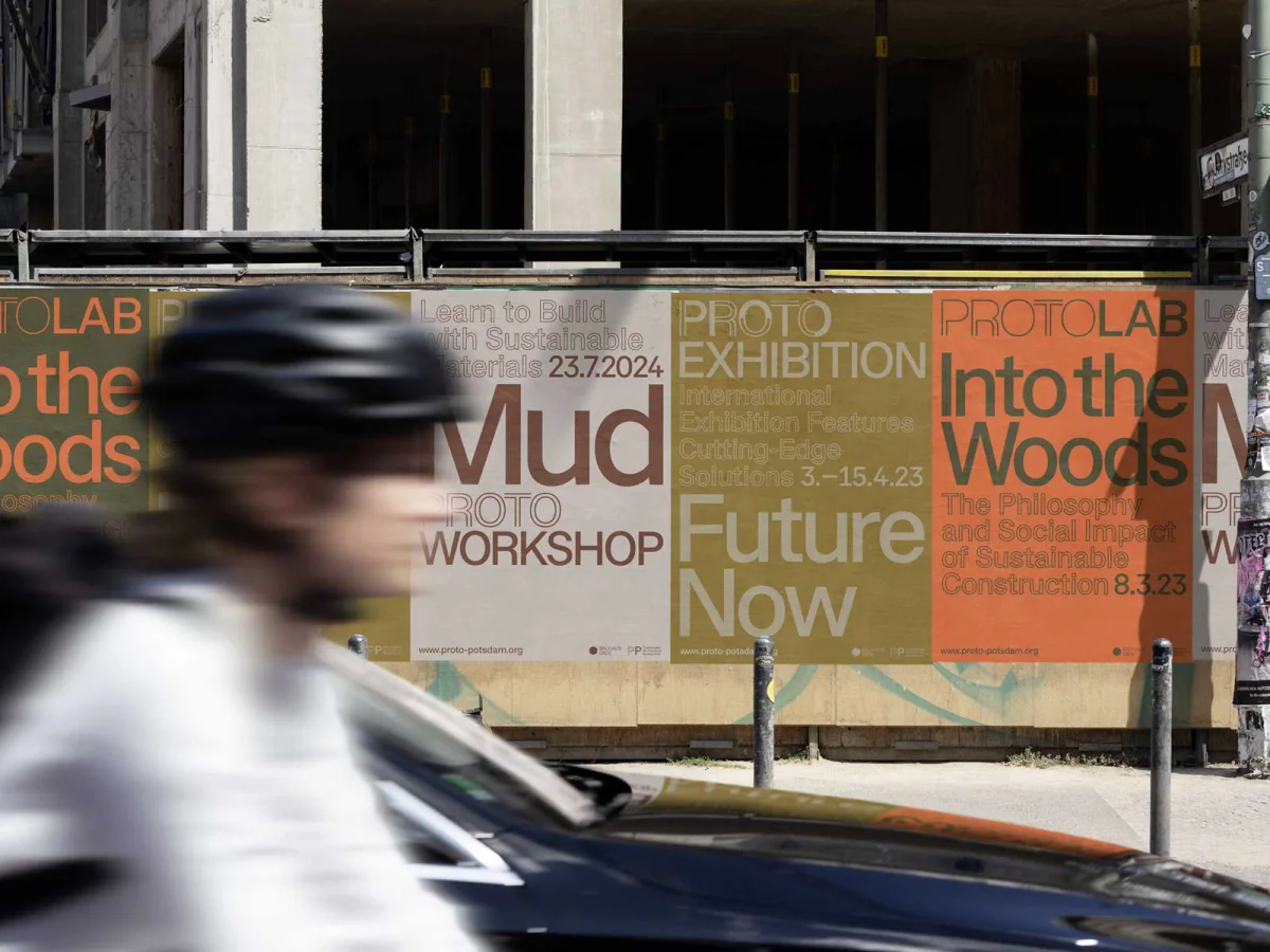 ProtoPotsdam poster series with large event titles on a construction fence, with a cyclist passing in the foreground.