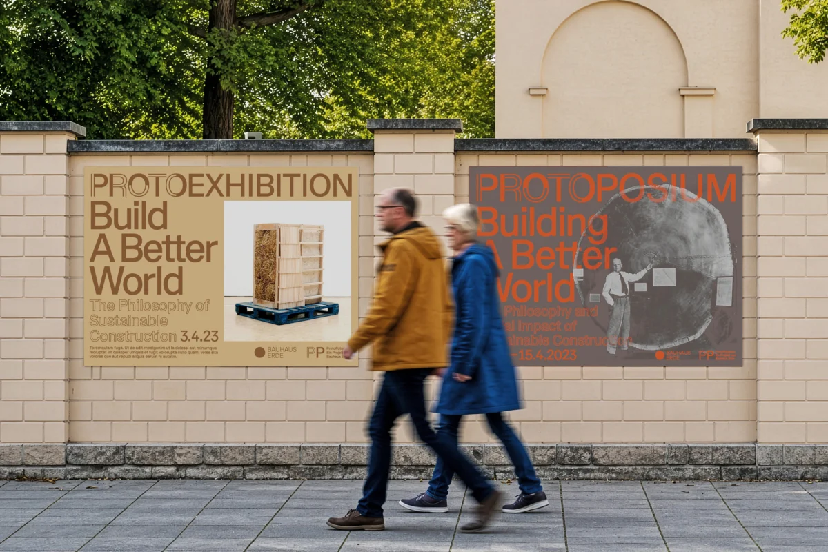 Two ProtoPotsdam “Build a Better World” posters on a wall, with two people walking past.