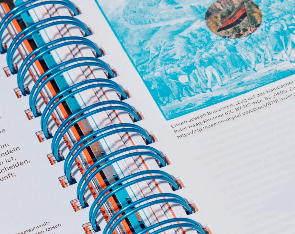 Detail of blue spiral binding beside a turquoise image and a small caption.
