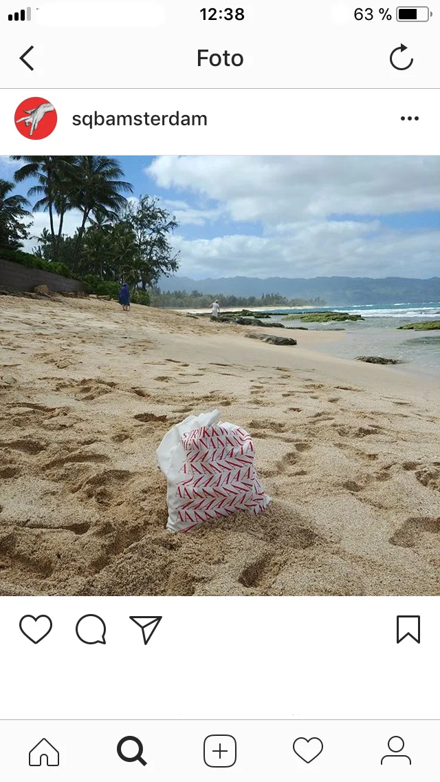 Instagram post showing a paper object printed with typography on a sandy beach.