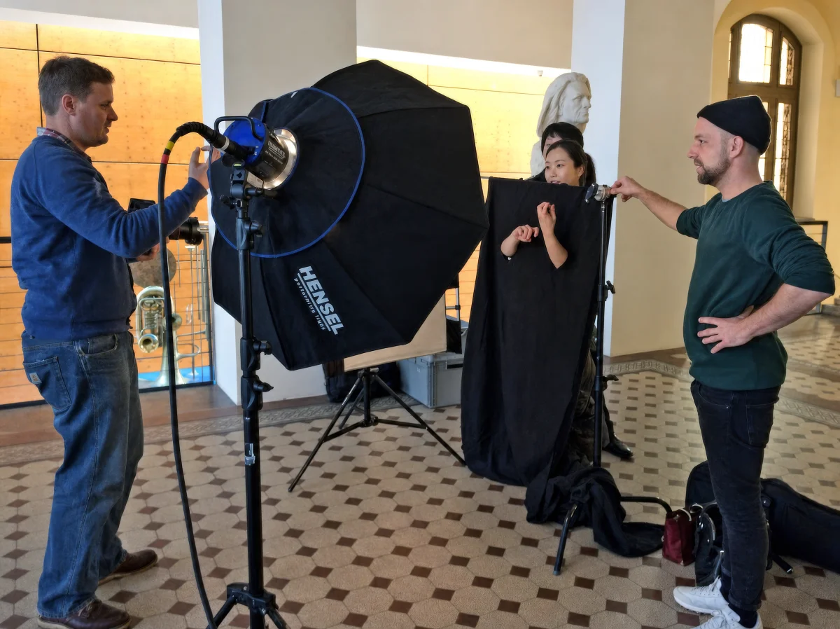 Biennale photo shoot with studio lighting and black fabric framing a person’s hands posed as if playing an instrument.