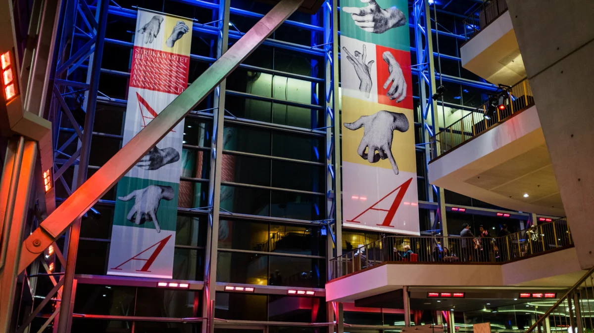 Tall banners with hand imagery and coloured lettering hanging across several storeys of the festival venue.